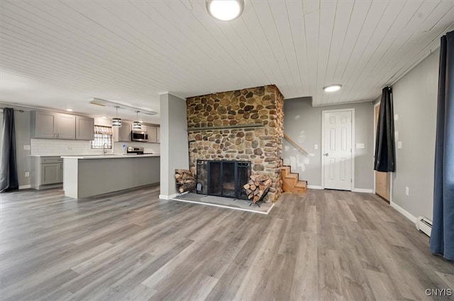 5640 Fearon Rd, Eaton, NY 13408 - unfurnished living room featuring a baseboard radiator, light wood-style flooring, stairs, wood ceiling, and a stone fireplace