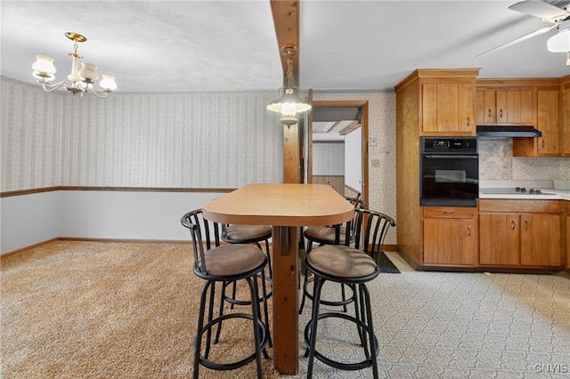 7165 Manlius Center Rd, Manlius, NY 13057 - kitchen with oven, wallpapered walls, ceiling fan, brown cabinetry, and hanging light fixtures