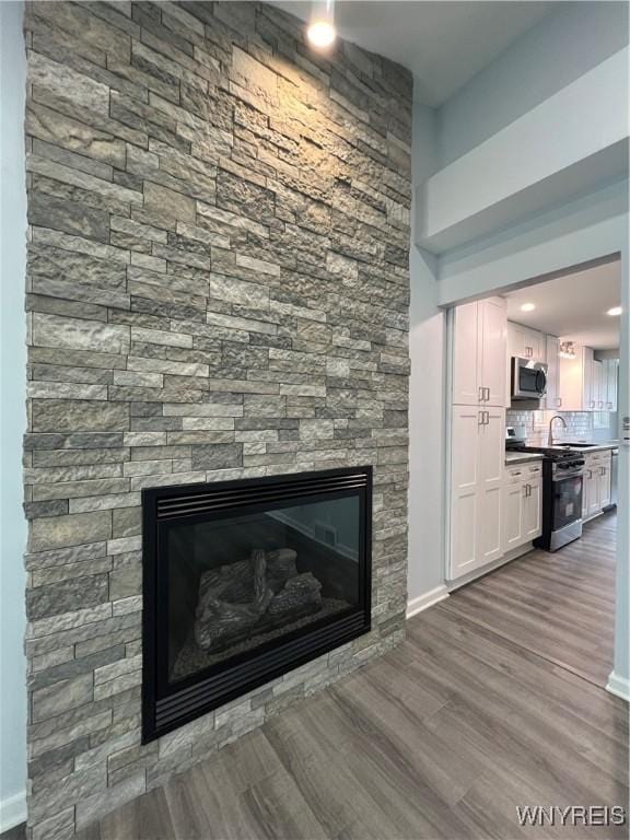 155 Barnsdale Ave, West Seneca, NY 14224 - detailed view of range with gas cooktop, wood finished floors, a fireplace, stainless steel microwave, and tasteful backsplash