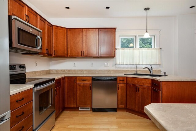 121 Reynolds Ave, Corning City, NY 14830 - kitchen with appliances with stainless steel finishes, light countertops, light wood finished floors, brown cabinetry, and hanging light fixtures