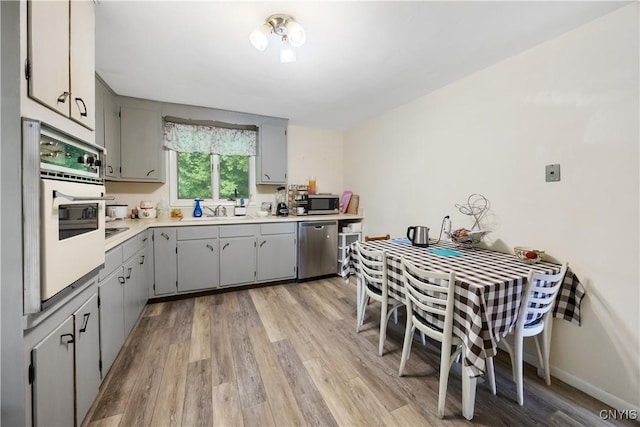 1018-20 Ackerman Ave, Syracuse, NY 13210 - kitchen with gray cabinets, light wood-style flooring, stainless steel appliances, and light countertops