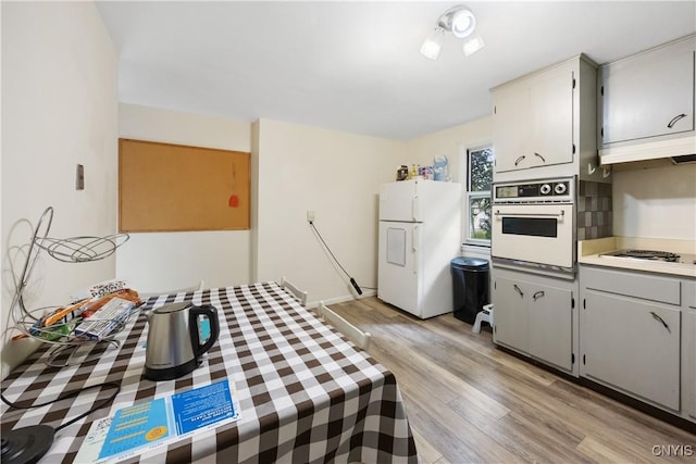 1018-20 Ackerman Ave, Syracuse, NY 13210 - kitchen featuring white appliances, light wood-type flooring, light countertops, under cabinet range hood, and gray cabinetry