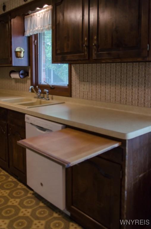 573 Locust St, North Tonawanda, NY 14120 - kitchen with wallpapered walls, white dishwasher, light countertops, and dark brown cabinets