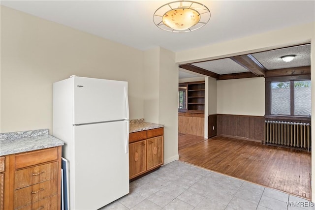 540 Longmeadow Rd, Amherst, NY 14226 - kitchen featuring freestanding refrigerator, radiator, light tile patterned flooring, a wainscoted wall, and beam ceiling