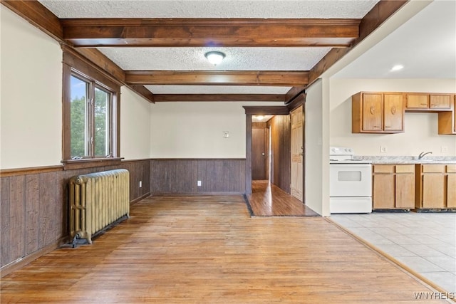 540 Longmeadow Rd, Amherst, NY 14226 - kitchen featuring beamed ceiling, radiator heating unit, light wood-style flooring, white electric range, and wainscoting