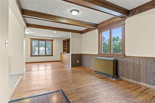 540 Longmeadow Rd, Amherst, NY 14226 - empty room featuring radiator, beamed ceiling, wainscoting, wood finished floors, and a textured ceiling