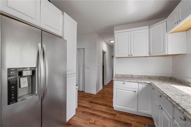 1142 Harlem Rd, Cheektowaga, NY 14227 - kitchen featuring stainless steel fridge, wood finished floors, white cabinets, and light stone counters