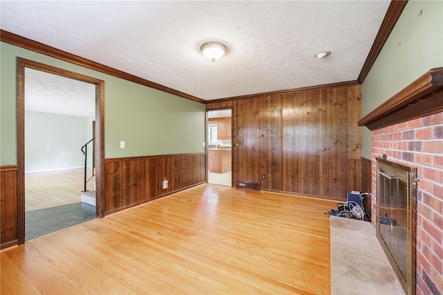 1225 Majestic Way, Webster, NY 14580 - unfurnished living room with wood walls, a brick fireplace, wood finished floors, wainscoting, and crown molding