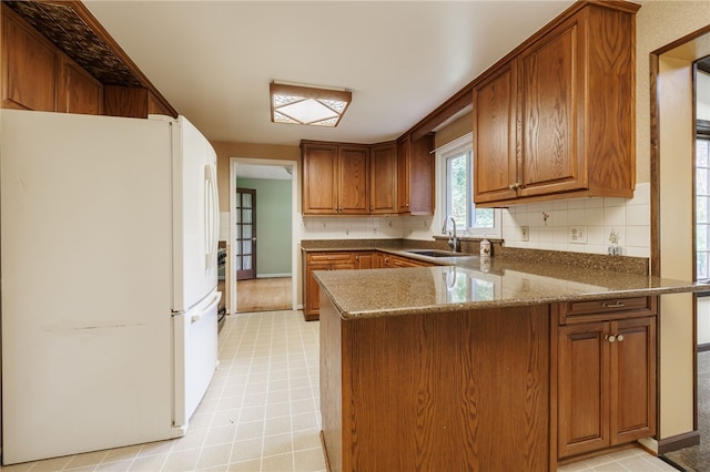 1225 Majestic Way, Webster, NY 14580 - kitchen with freestanding refrigerator, a peninsula, brown cabinets, and decorative backsplash