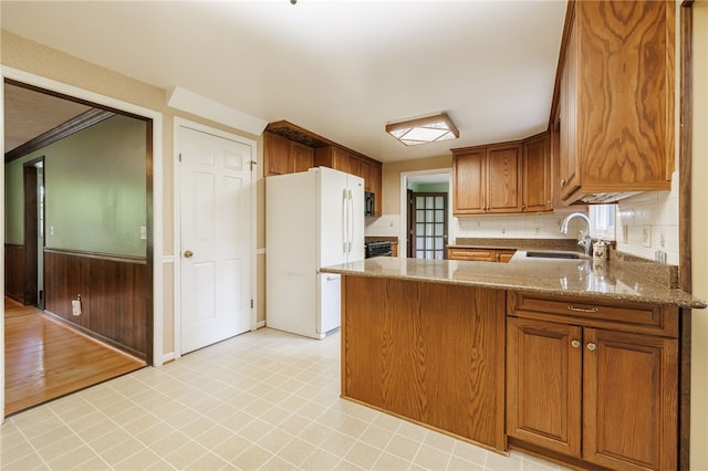 1225 Majestic Way, Webster, NY 14580 - kitchen featuring freestanding refrigerator, a peninsula, light stone counters, brown cabinets, and backsplash