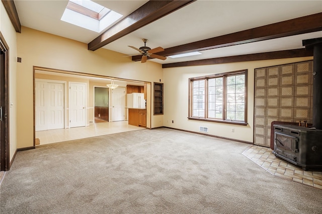 1225 Majestic Way, Webster, NY 14580 - unfurnished living room featuring a wood stove, a skylight, carpet floors, beam ceiling, and ceiling fan