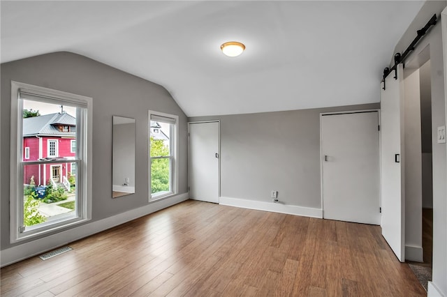 373 Rhode Island St, Buffalo, NY 14213 - empty room with a barn door, wood finished floors, lofted ceiling, and plenty of natural light