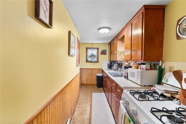 235 Wagner Ave, Cheektowaga, NY 14212 - kitchen featuring wainscoting, white appliances, light countertops, brown cabinetry, and wooden walls