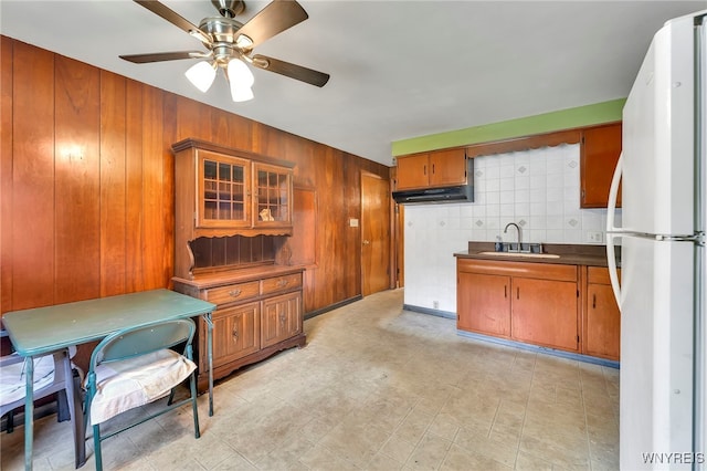 85 Pacific Ave, Lackawanna, NY 14218 - kitchen with freestanding refrigerator, brown cabinetry, ceiling fan, wooden walls, and dark countertops