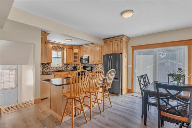 67 Amber St, Buffalo, NY 14220 - kitchen featuring stainless steel appliances, light wood-type flooring, tasteful backsplash, and a breakfast bar area