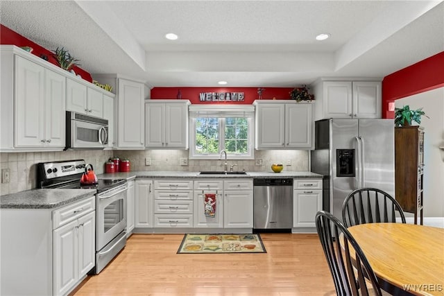 6 Fair Woods Dr, Amherst, NY 14221 - kitchen featuring stainless steel appliances, a raised ceiling, light wood-style flooring, white cabinetry, and recessed lighting