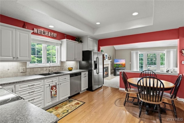 6 Fair Woods Dr, Amherst, NY 14221 - kitchen with light wood-style flooring, appliances with stainless steel finishes, white cabinets, a tray ceiling, and backsplash