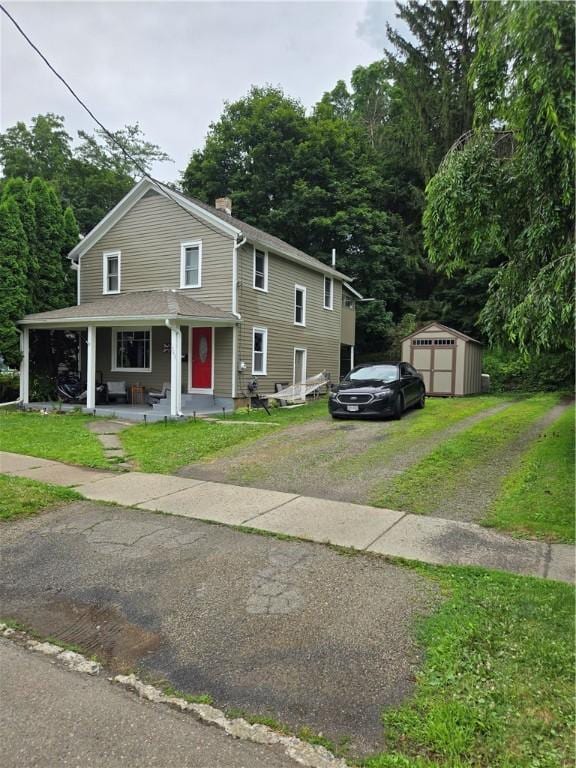 262 E 3rd St, Corning City, NY 14830 - view of front facade with driveway, a porch, a chimney, a front yard, and a storage unit