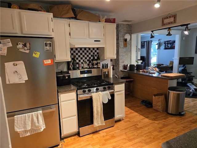 262 E 3rd St, Corning City, NY 14830 - kitchen with stainless steel appliances, dark countertops, light wood finished floors, under cabinet range hood, and white cabinets