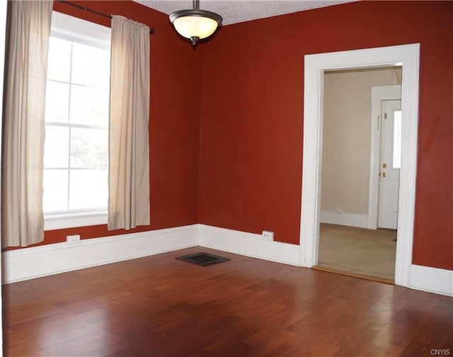 unfurnished room with plenty of natural light, a textured ceiling, and dark hardwood / wood-style flooring