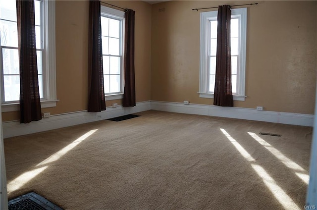 spare room featuring light carpet and plenty of natural light