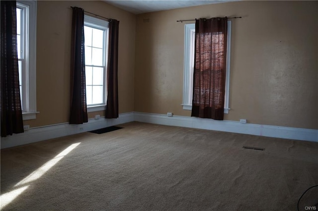 unfurnished room with a wealth of natural light and carpet