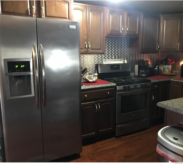 kitchen with range with gas stovetop, tasteful backsplash, dark brown cabinets, stainless steel fridge, and dark hardwood / wood-style flooring