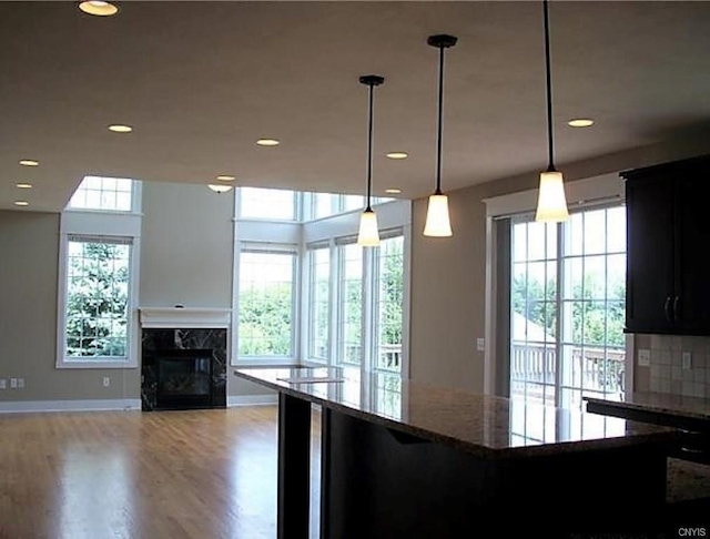 kitchen featuring dark stone counters, wood-type flooring, pendant lighting, and a premium fireplace