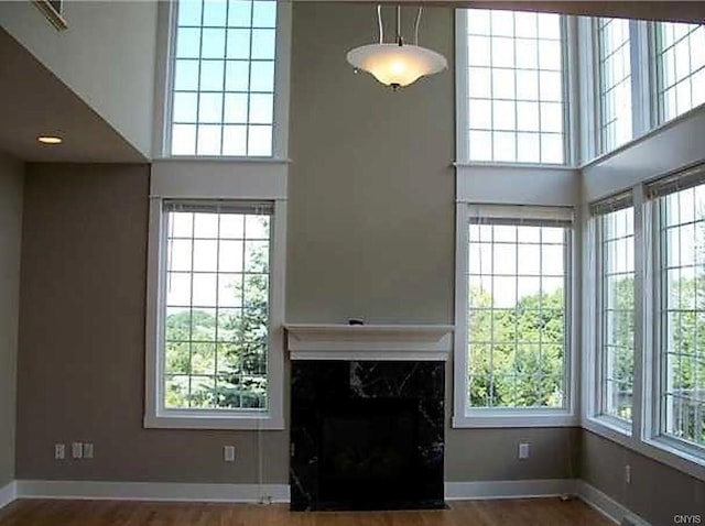 unfurnished living room with dark hardwood / wood-style floors, a high end fireplace, and a wealth of natural light