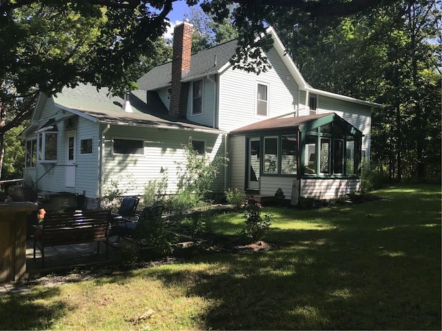 back of property with a sunroom and a lawn