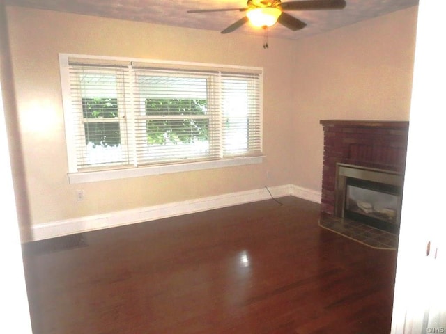 unfurnished living room with dark wood-type flooring, ceiling fan, and a fireplace