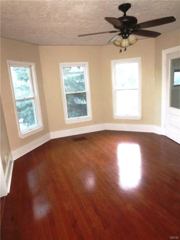 unfurnished room with ceiling fan, a textured ceiling, and dark hardwood / wood-style flooring