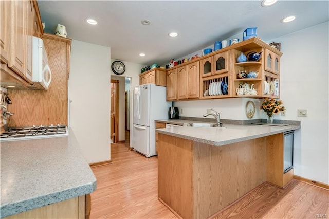 kitchen featuring white appliances, sink, light hardwood / wood-style floors, and kitchen peninsula