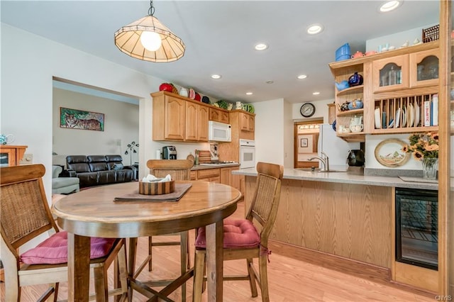 kitchen featuring pendant lighting, kitchen peninsula, wine cooler, light hardwood / wood-style flooring, and white appliances