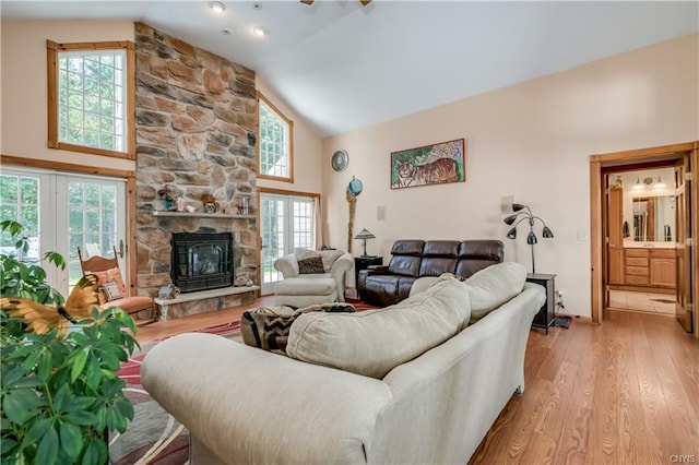 living room with light hardwood / wood-style floors, high vaulted ceiling, and a fireplace