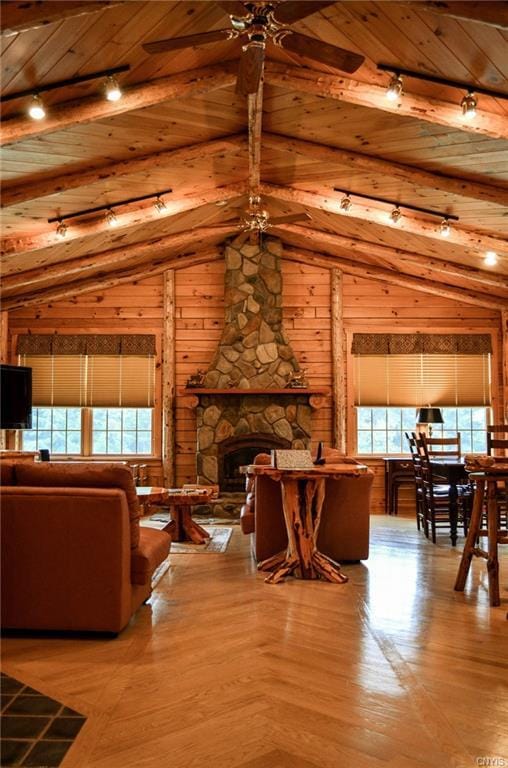 living room with wood ceiling, a stone fireplace, ceiling fan, and a wealth of natural light