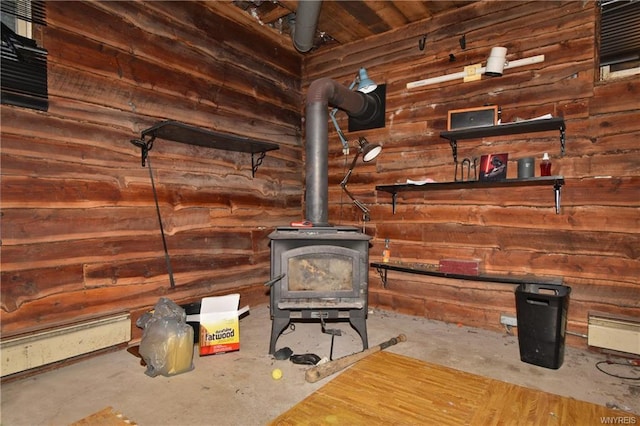 unfurnished living room with log walls, a wood stove, and concrete floors