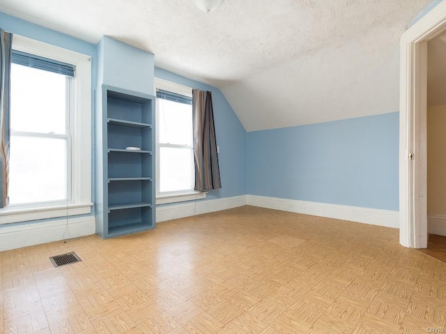 bonus room featuring a textured ceiling, light parquet flooring, and vaulted ceiling