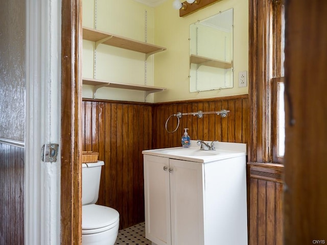 bathroom with toilet, tile floors, wood walls, and vanity with extensive cabinet space