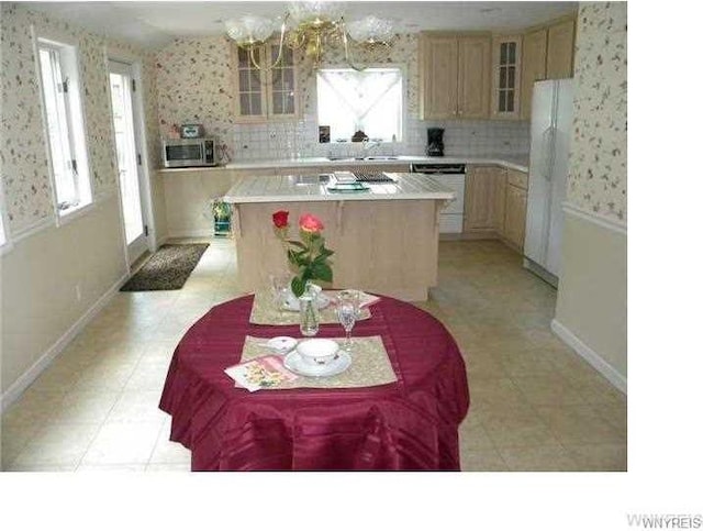 kitchen with tasteful backsplash, light brown cabinets, a notable chandelier, and a center island