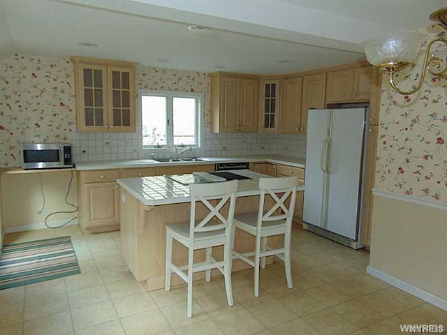 kitchen with a center island, tasteful backsplash, a kitchen breakfast bar, sink, and white refrigerator