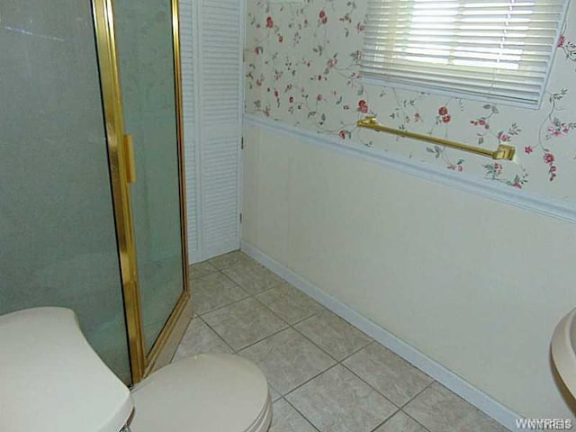 bathroom with toilet, tile flooring, and a shower with shower door