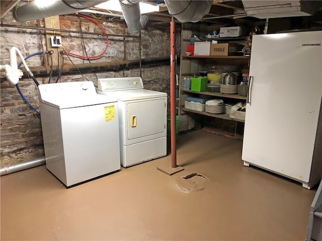 basement featuring washing machine and dryer and white fridge