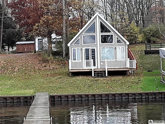 rear view of house with a lawn, a water view, and a storage unit