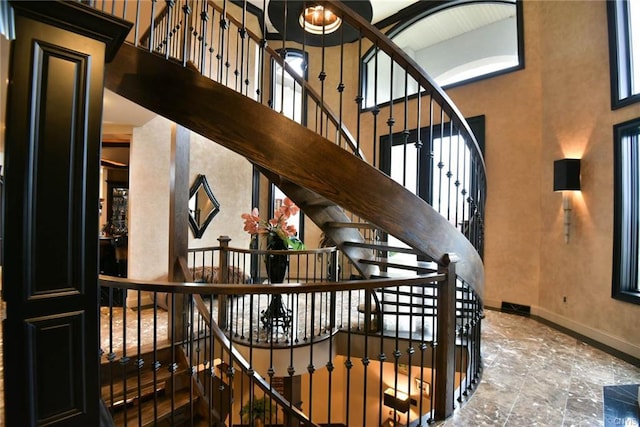 stairway with dark tile flooring, an inviting chandelier, and a towering ceiling