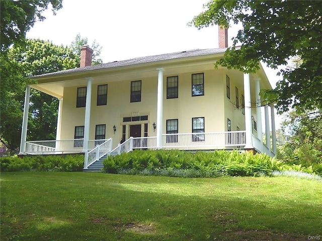 rear view of house featuring a yard and a porch