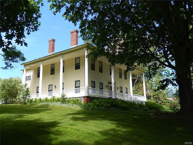 rear view of house featuring a yard and covered porch