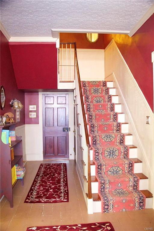 staircase with crown molding, light tile floors, and a textured ceiling