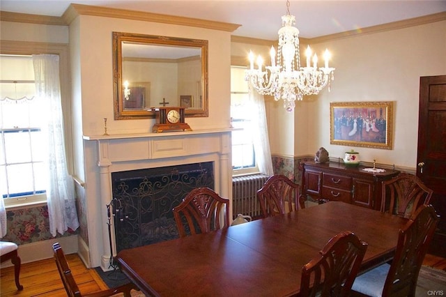 dining space featuring ornamental molding, light hardwood / wood-style floors, a chandelier, and radiator heating unit