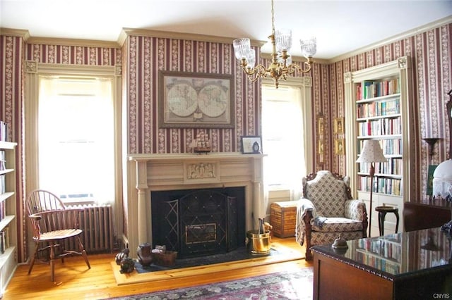 living area featuring a notable chandelier, crown molding, a healthy amount of sunlight, and light hardwood / wood-style floors